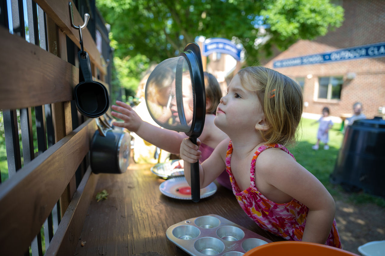 Children playing with kitchen items in an outdoor classroom